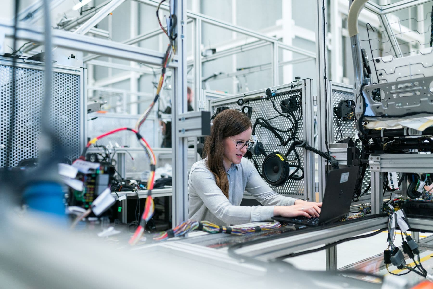 Technician running diagnostics on a laptop next to electromechanical equipment